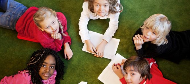 Barn ligger på gulvet og tegner.