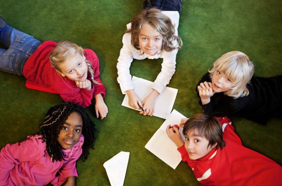 Barn ligger på gulvet og tegner.